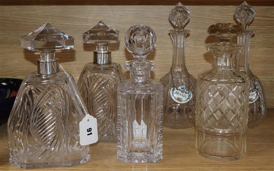 A pair of 1930s shaped square-section engraved glass decanters with silver collars and pyramid stoppers and four other decanters,